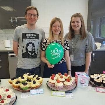 staff posing with their cupcakes at a charity bake sale
