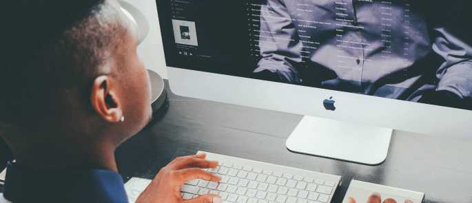 man sitting at an apple mac looking at the screen