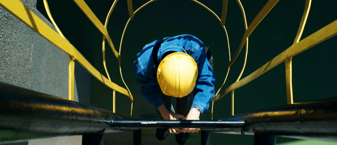 Worker climbing a ladder into an excavation site