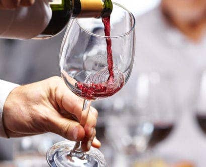 Waiter pouring wine into a wine glass in restaurant