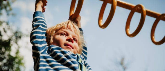 A little boy on monkey bars