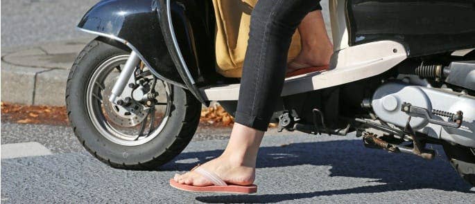 A woman wearing flip flops on a motorbike 