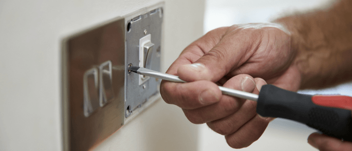 Licensed electrician carrying out maintenance on a light switch