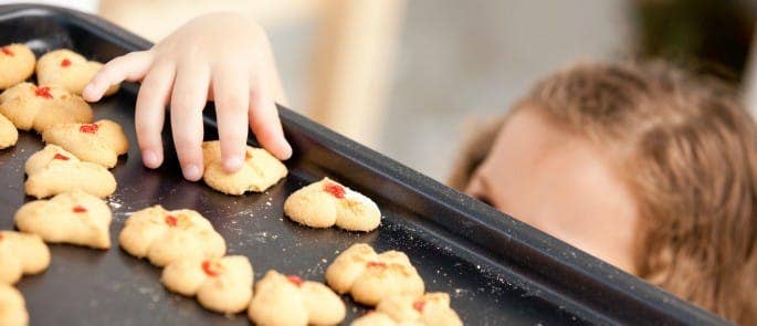 Child taking cookie off a baking tray