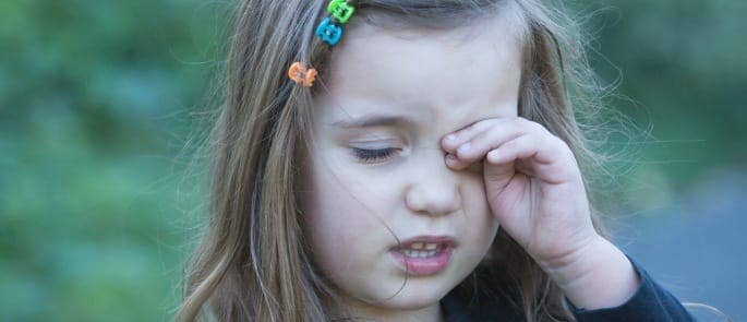 child looking unhappy with hand to her face