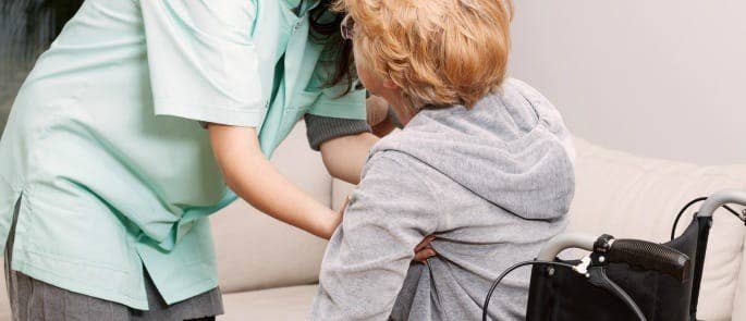 elderly patient being helped out of wheelchair by nurse