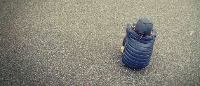 Little boy sat in the school playground alone and isolated