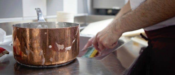 A restaurant chef cleaning a pan