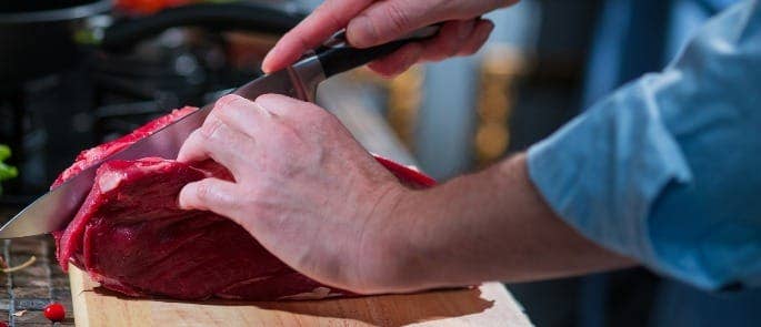 Chef slicing raw cut of beef