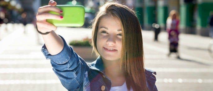 Teenager using Snapchat on her mobile phone to send a selfie