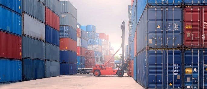 red cargo lorry surrounded by shipping containers