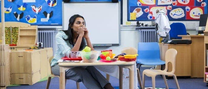 Primary school teacher sat at table thinking about safeguarding concern