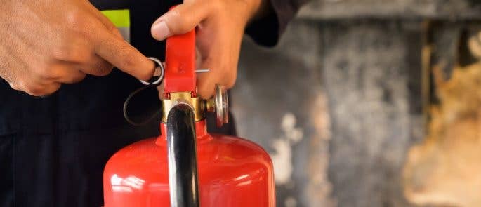 Person pulling the pin out of extinguisher