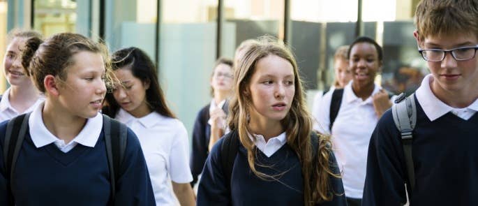 Teenagers in uniform walking through the school playground