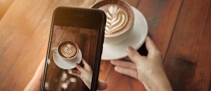 Instagram user taking a photo of a cappuccino to post online