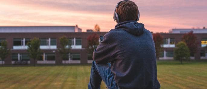 Teenage boy sat on a hill with headphones on