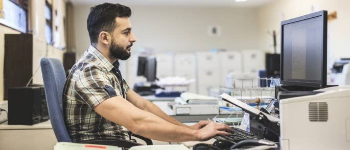 Man sitting at a computer looking at private data 