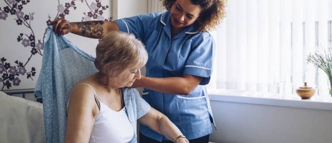 Carer helping an elderly woman to get dressed