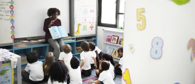 Primary school teacher reading a book to children