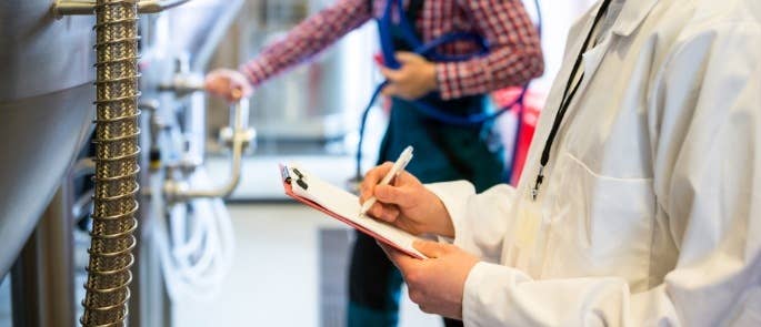 Worker carrying out a check of food manufacturing equipment