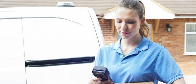 Deliver driver next to van holding a parcel and a handheld device