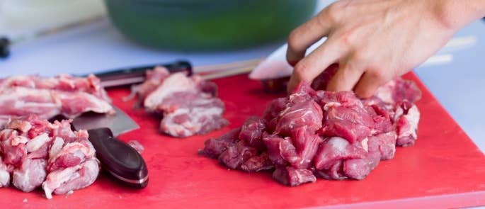 Woman dicing raw lamb