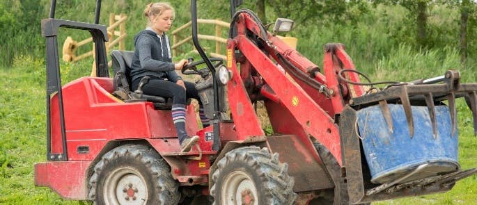 Farmer using lifting equipment on her farm