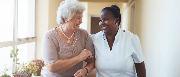 Healthcare provider and patient walking through care home with positive relationship