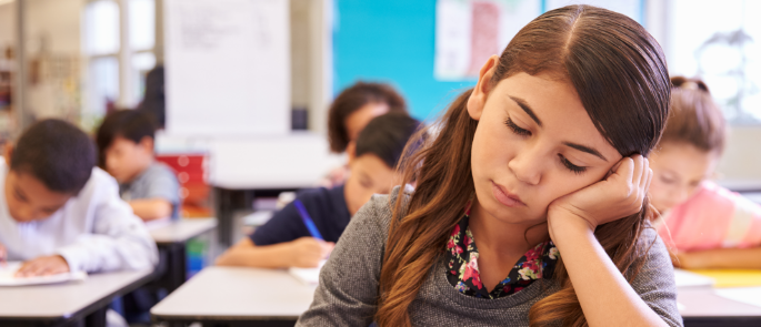 Girl sits with head resting on hand