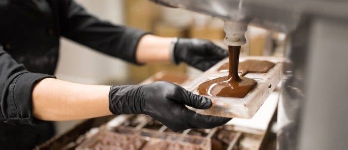 Chocolatier using a machine to pour potentially fraudulent chocolate into a plastic mould 