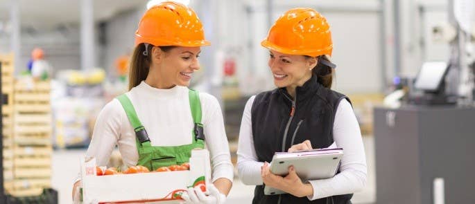 Two women in a food warehouse with clipboards 