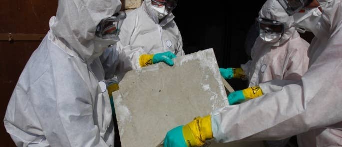 Asbestos removal experts putting asbestos in a bag