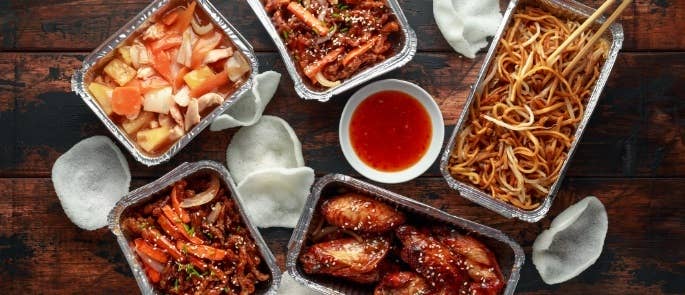 Chinese takeaway food including noodles and chicken in metal containers