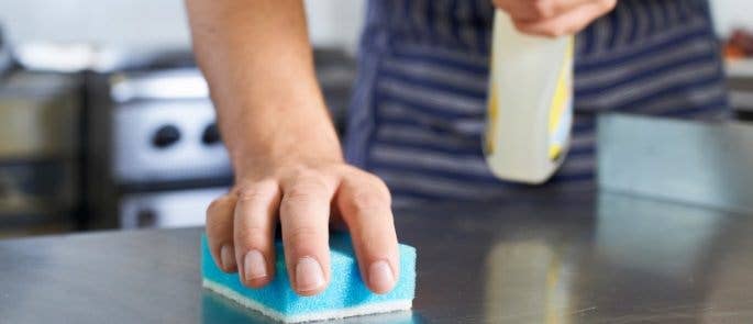 Man using cleaning chemicals to clean the kitchen surfaces