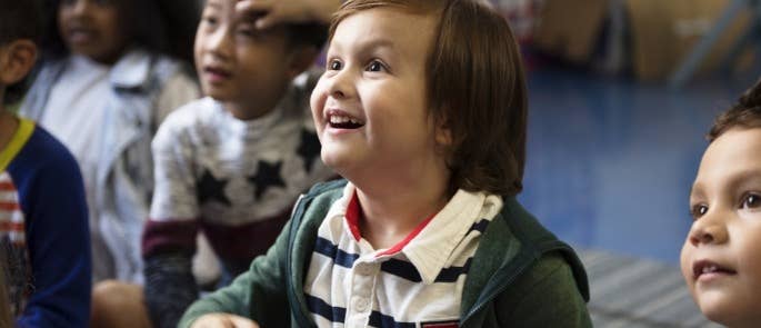 A happy child in class listening to the teacher