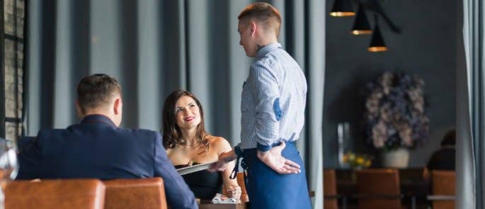 Waiter at a table taking the food orders of a couple