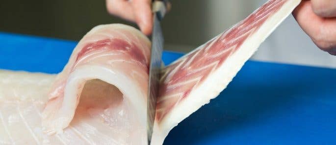 Cutting raw fish on a blue chopping board