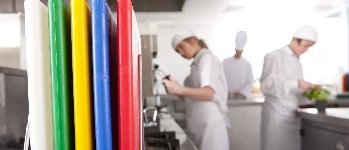 A group of coloured chopping boards in a catering kitchen