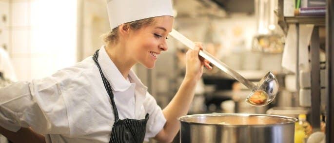 Female chef stills big stock pan on stove