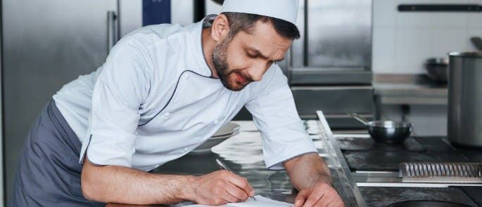 Head chef writing his risk assessment notes in the kitchen