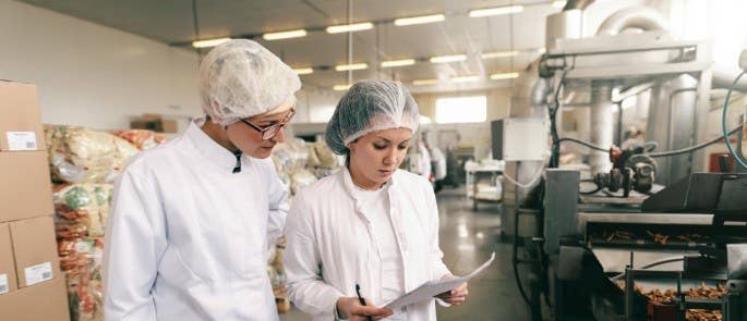 Two women check paperwork together in a food processing plant