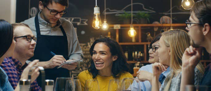 A group of people in a restaurant with a waiter taking their orders