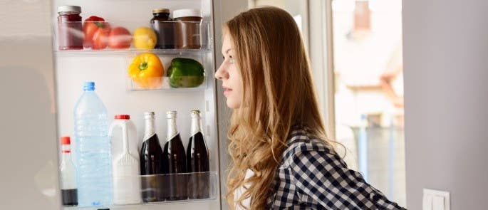 Young woman looks in fridge