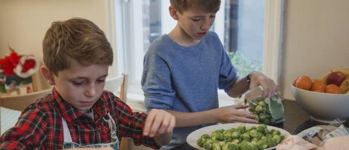 Two brothers prepare sprouts with cranberies for Christmas dinner