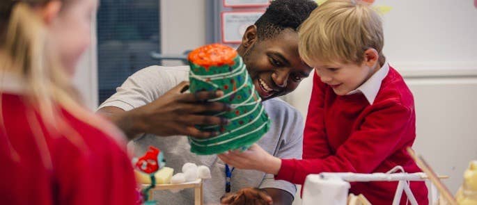 Male teacher helping primary school children with crafts