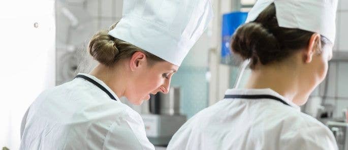 Two female chefs wearing hats in the kitchen