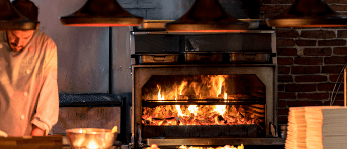 Chef working alone infront of a hot flame oven.