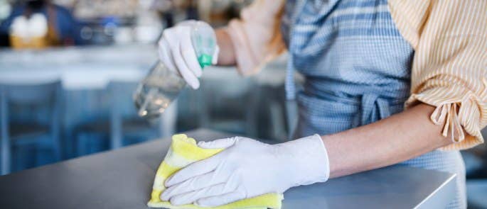 Worker in cafe disinfects counter top