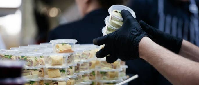 People wearing gloves to prepare food for takeaway