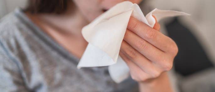 Woman coughing into a tissue